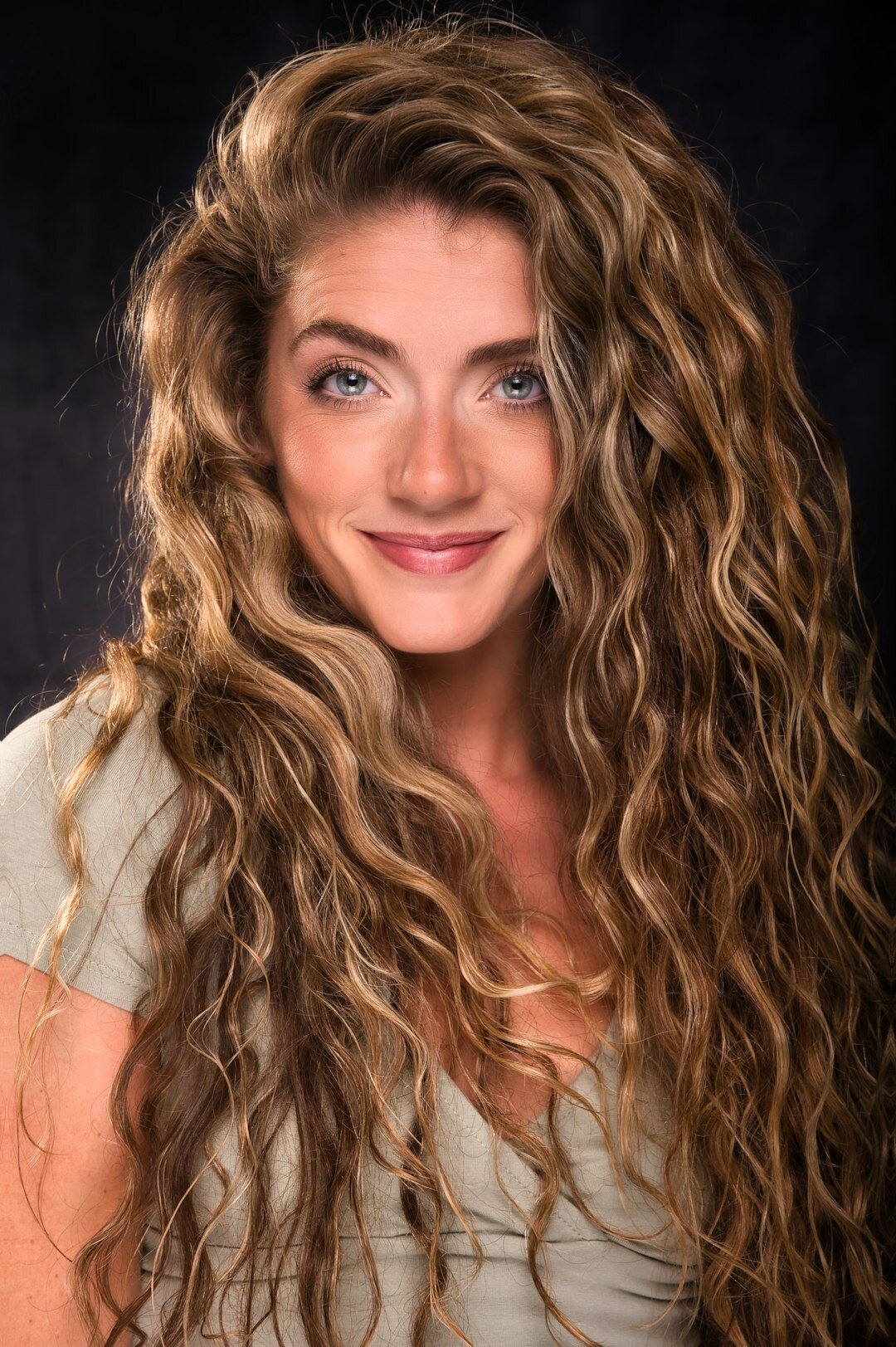Studio portrait of a smiling woman with curly hair
